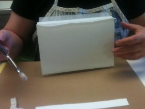 Heidi paints glue on the spine